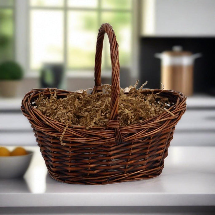 Woven wicker gift basket filled with shredded filler and a tall handle
