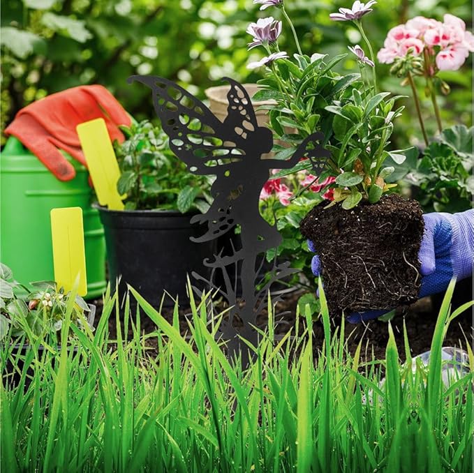 Black fairy garden stake silhouette in a flower bed among green plants