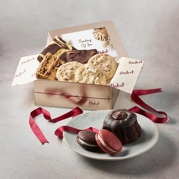 Gift tin with assorted cookies and pastries, red ribbon, and greeting card