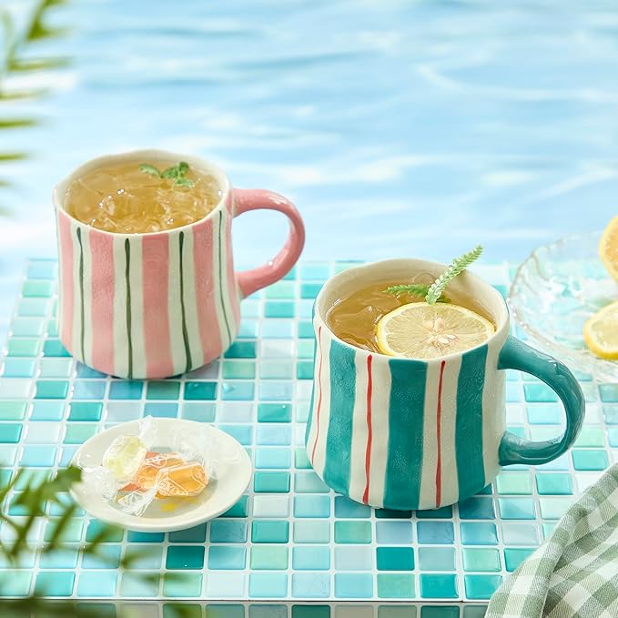 Pair of ceramic coffee mugs with pink-and-green vertical stripes and curved handles