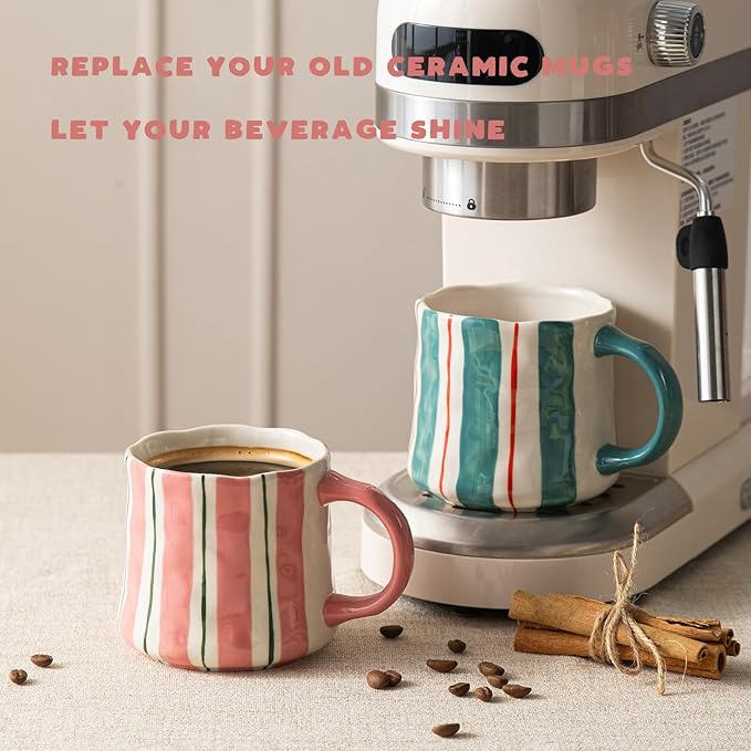 Ceramic striped mugs near a coffee maker, one pink-handle and one green-handle