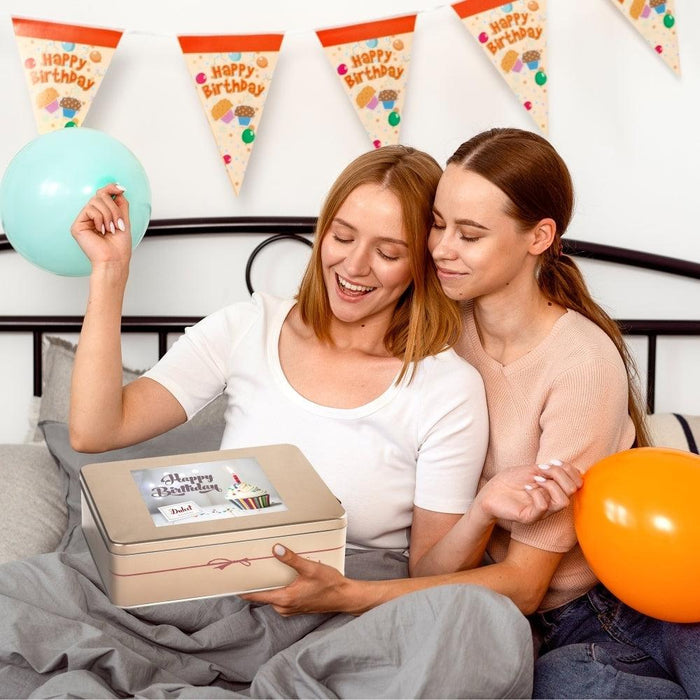 Birthday gift tin held by two people, balloon and gift box label visible