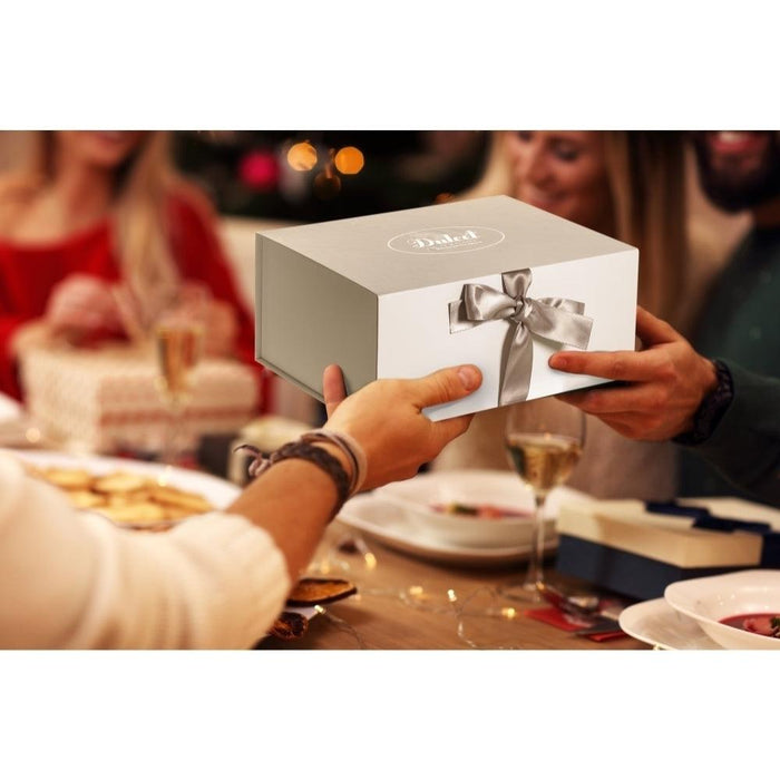 White ribboned gift box held by hands on a dining table