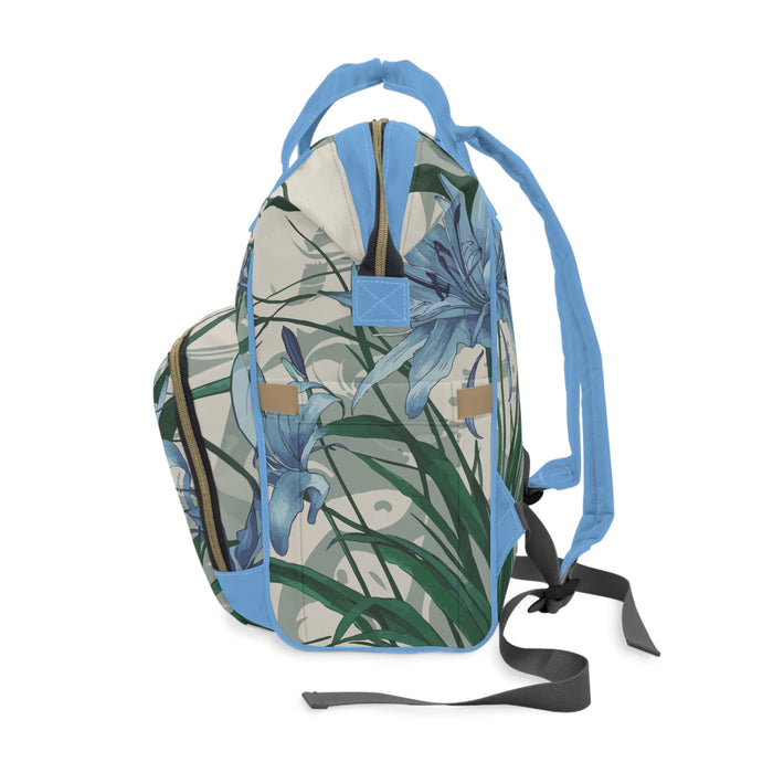 Diaper backpack with blue shoulder straps and floral print, side view with front flap