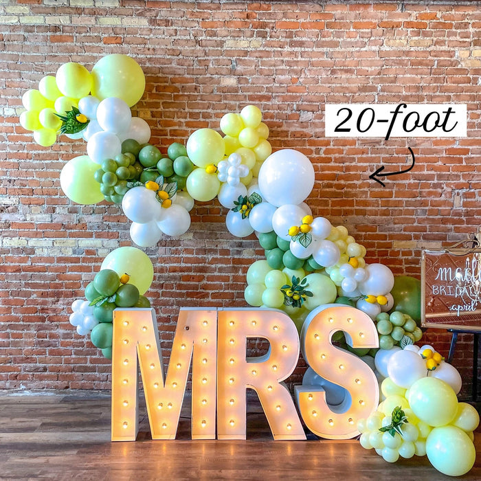 Balloon garland kit with lemon yellow, green, and white balloon clusters and letter balloons