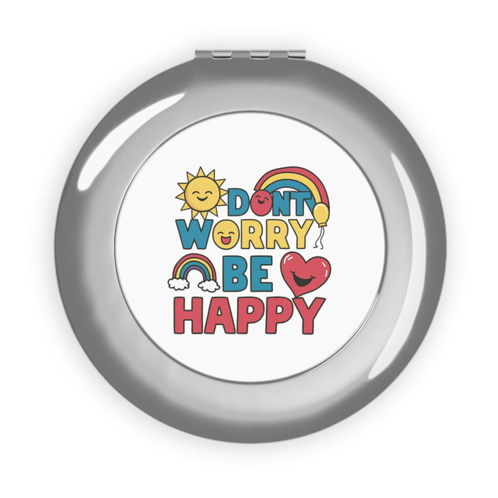 Silver glossy compact travel mirror with “DON'T WORRY BE HAPPY” printed on cover