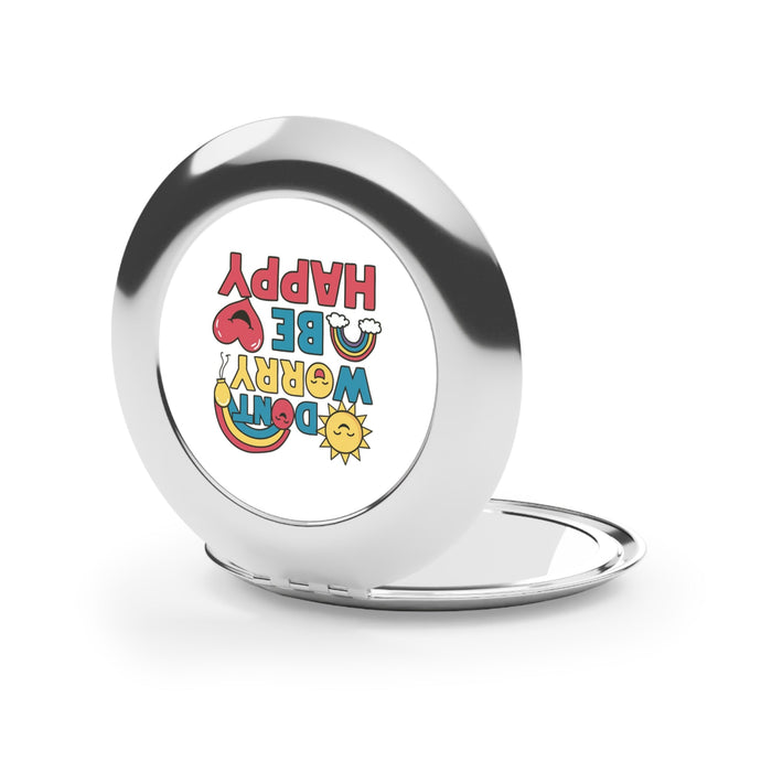 Silver glossy compact travel mirror with circular frame and “DON'T WORRY BE HAPPY” graphic