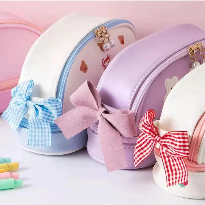 Light purple double-compartment pencil bag with ribbon bows and heart charm zippers.