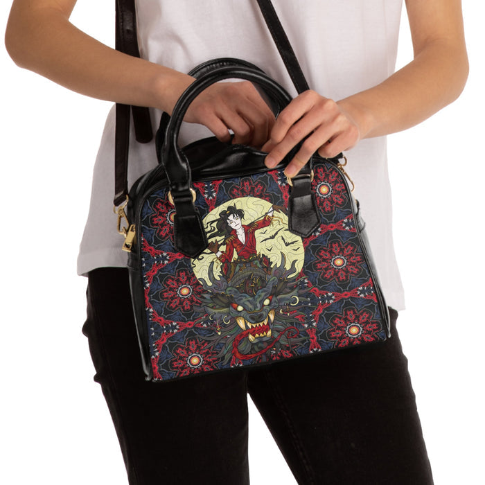 Black handle handbag held by person; red patterned front with central illustrated graphic