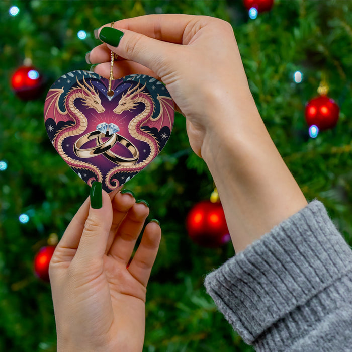 Heart-shaped ceramic ornament with dragon heads and wedding rings, held in hand