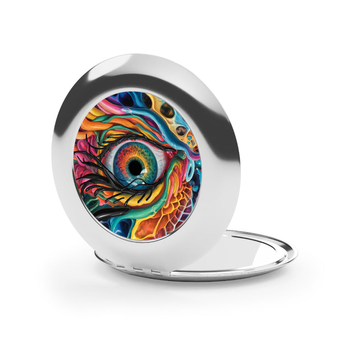 Silver glossy compact mirror with dragon-eye artwork on lid, open with reflective insert