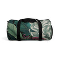 Botanical duffel bag with green leafy print, black straps, and zip end panels