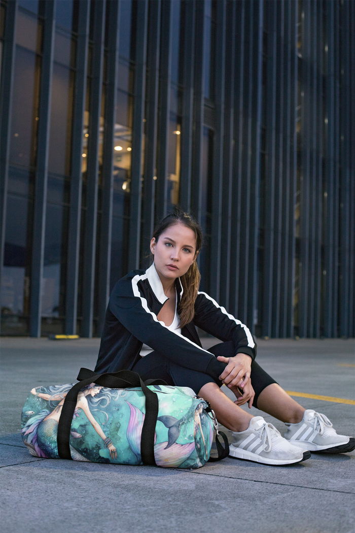 Mermaid print duffel bag with black straps, resting on the ground