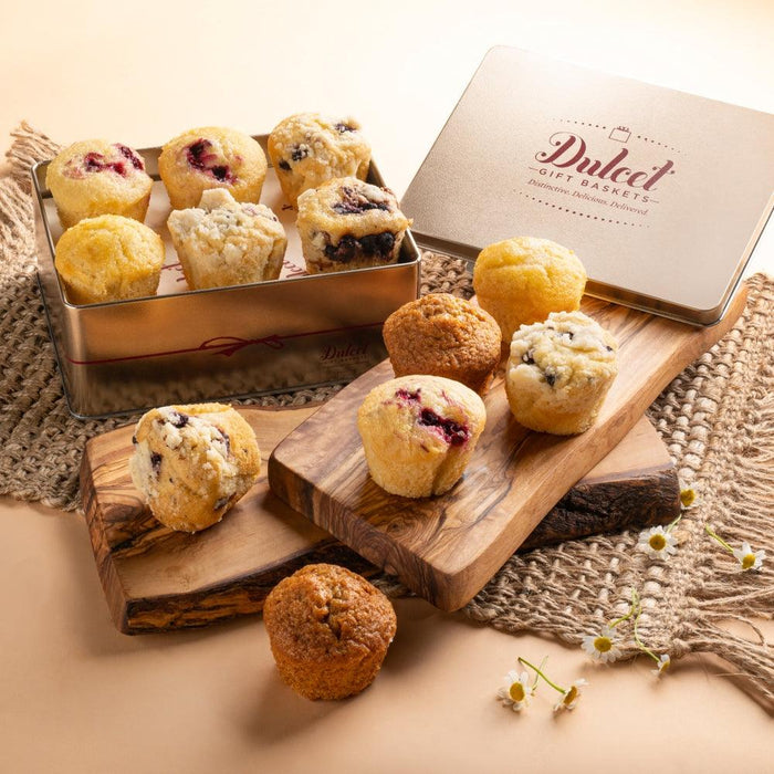 Gold tin filled with assorted muffins on a wooden board