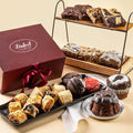 Burgundy gift box with red ribbon, assorted pastries and cookies on tray