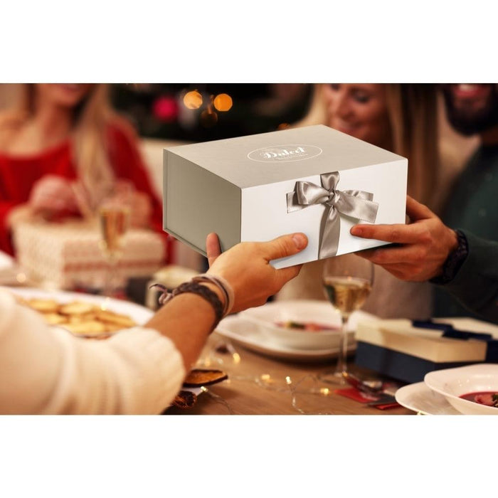 White gift box with satin gray ribbon being handed to someone at a table