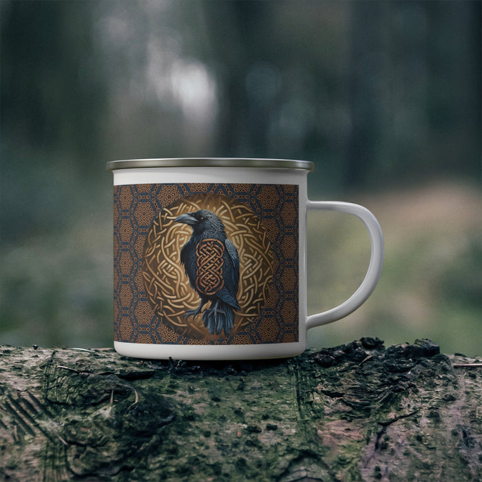 Enamel camping mug on tree bark, blue-brown pattern with raven and gold knot emblem