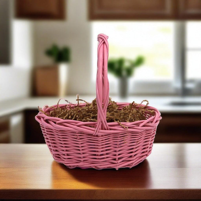 Pink wicker gift basket with ribbon handle and straw filler