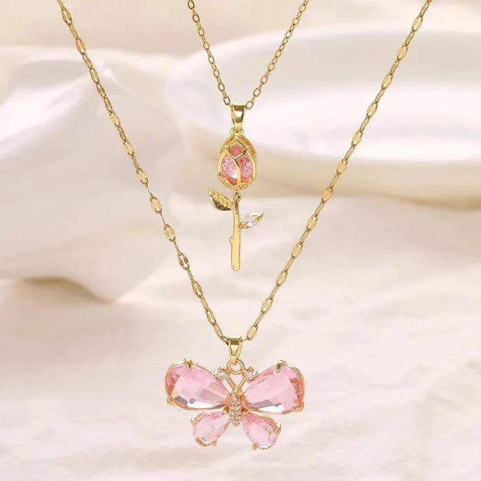 Gold-tone butterfly flower necklace with pink gem petals and rose bud drop charm