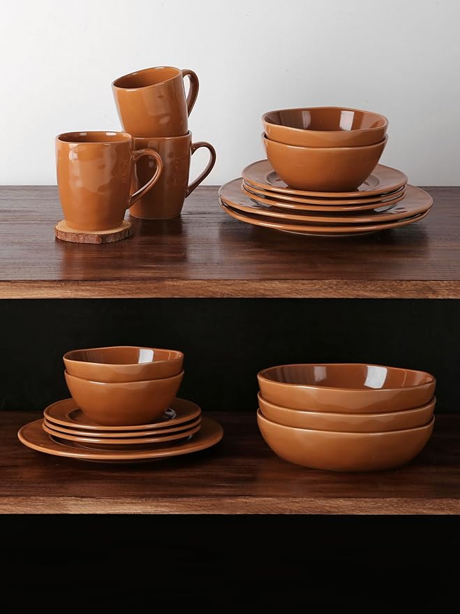 Four brown stoneware coffee mugs with glossy reactive glaze, set arranged on table