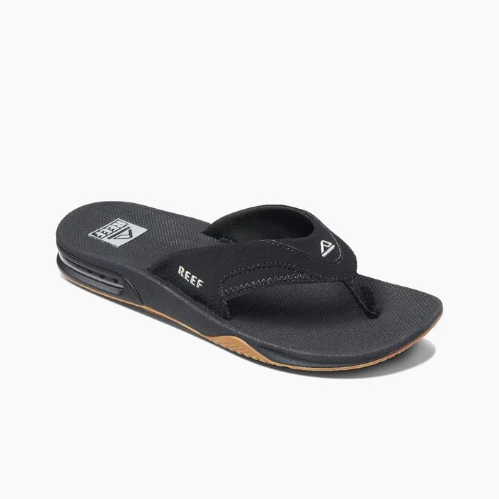 Reef Fanning Flip Flops in black with synthetic straps, cushioned footbed, and brown rubber outsole, angled side view.