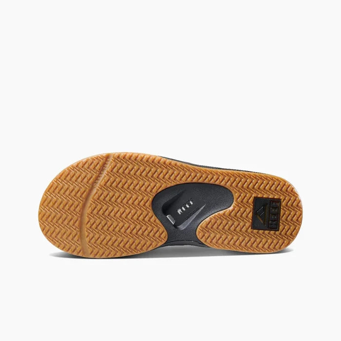 Reef Fanning Flip Flops outsole with rubber herringbone tread in tan and bottle opener feature in black, bottom view