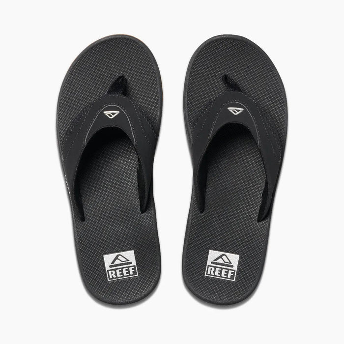 Reef Fanning Flip Flops in black with textured footbed, logo detail on straps, and built-in bottle opener, top view.