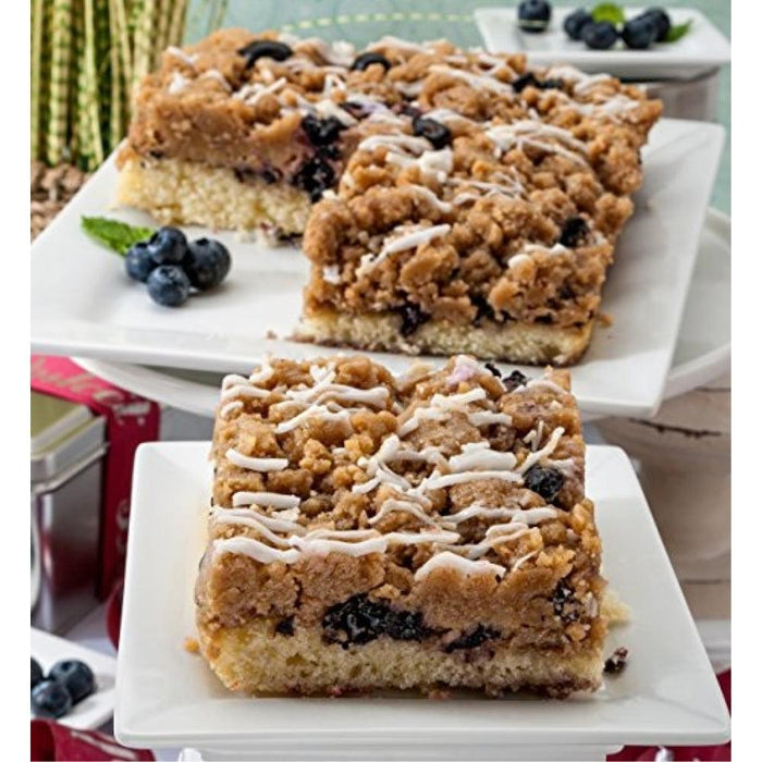Blueberry crumb cake slices with crumb topping, white icing drizzle, and blueberries