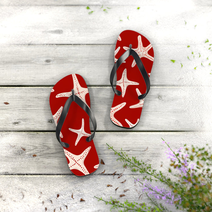 Red flip flops with white starfish print and black thong straps, pair