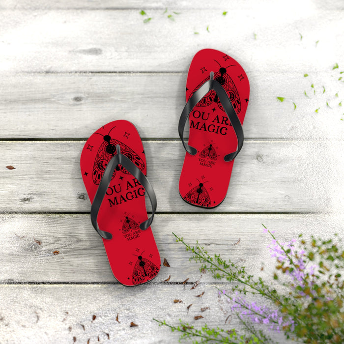 Pair of red flip-flops with black thong straps and printed “You are Magic” footbed