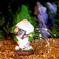 Solar garden gnome statue with green hat, white beard, holding watering can, lit wire lights