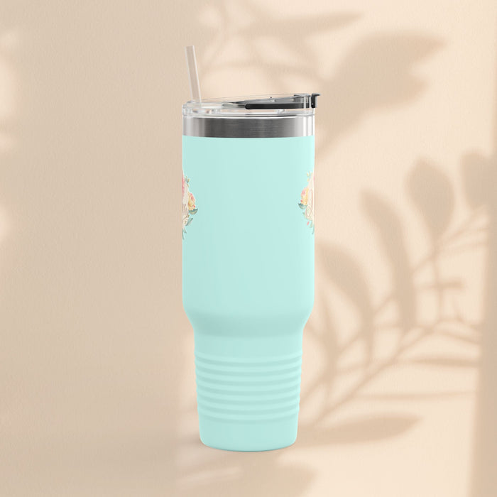 Light teal insulated travel mug with small floral accents near top, clear lid and straw