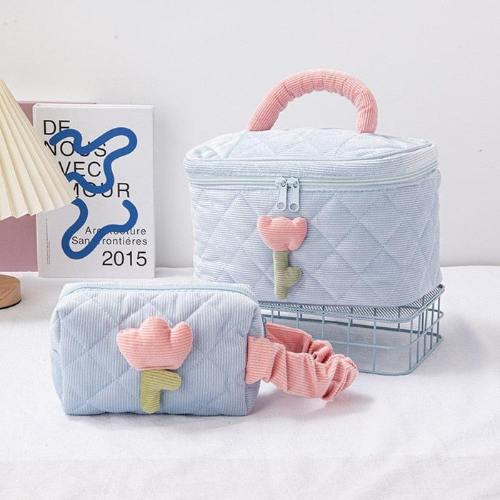 Quilted light blue makeup bag with heart flower charm and carry handle, zip top