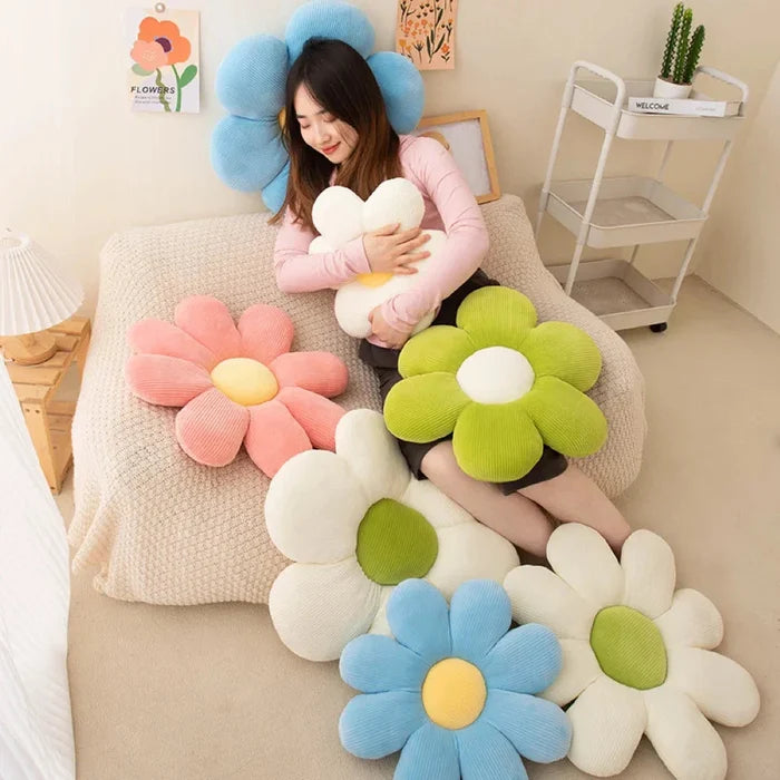 Flower-shaped plush pillows arranged on a couch with white, green, blue, and pink blooms