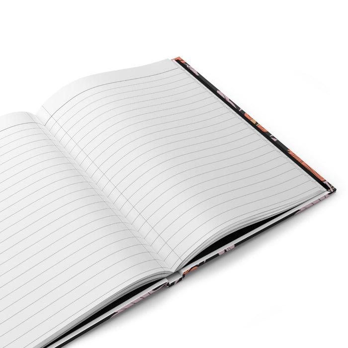 Open hardcover journal with lined pages and black floral cover edges.