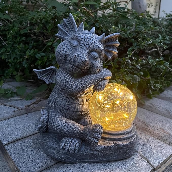 Blue-gray dragon resin figurine holding a glowing glass orb, illuminated outdoor statue