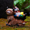 Gnome on highland cow garden statue holding a glowing solar cup light