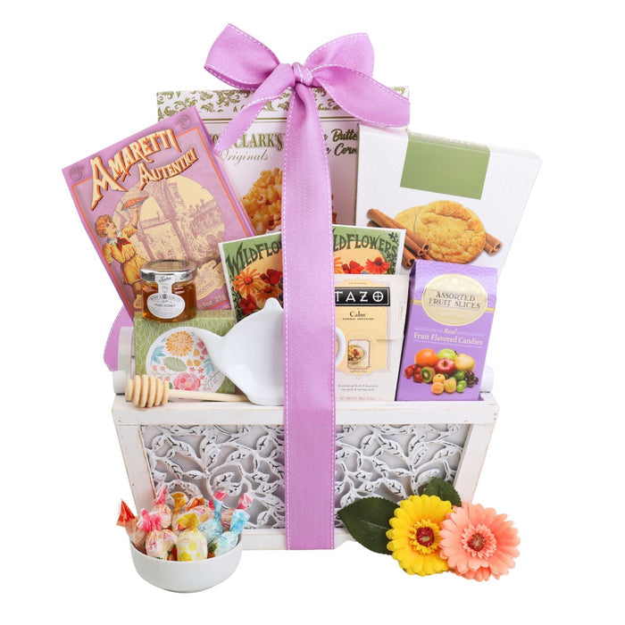 Gourmet gift basket with purple bow, tea, cookies, and colorful candy with gerbera flowers