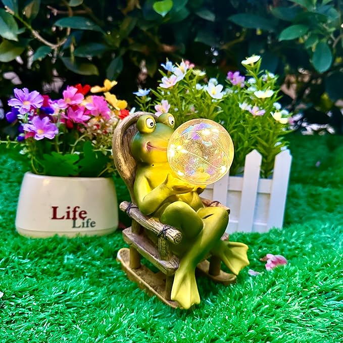 Garden frog resin statue on wooden rocker with glowing bubble light among flowers