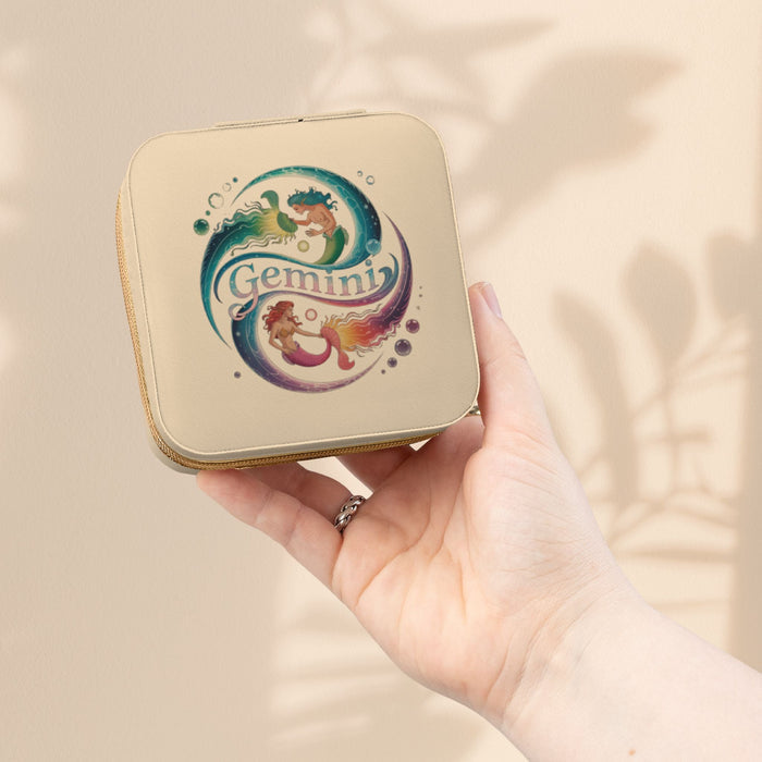 Ivory zippered jewelry travel case with Gemini zodiac graphic, held in hand.