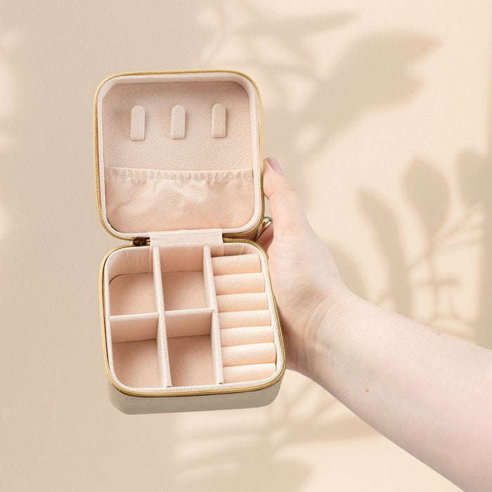 Pink compact jewelry organizer travel case open with ring and earring slots.