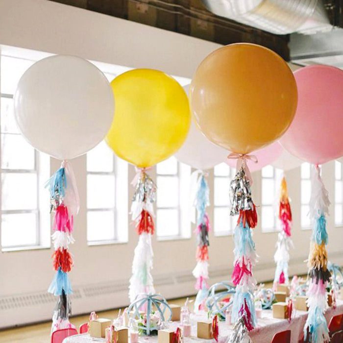 Pastel giant balloons with fringe tassel strings in white, yellow, and blush