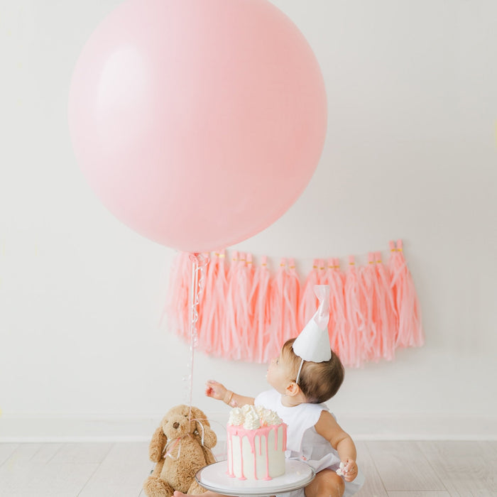 Pink giant balloon with hanging tassel fringe and coordinating ribbon knots
