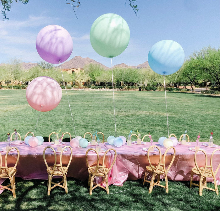 Outdoor party table with pastel giant balloons floating above