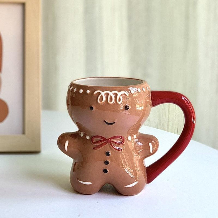 Gingerbread man mug with brown cookie body, red bow, smiling face, and red handle