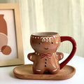 Gingerbread man mug with brown cookie design, red bow, smiling face, and red handle