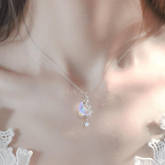 Silver moon pendant necklace with blue iridescent crescent charm and star accents on chain