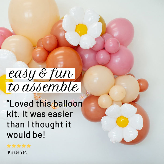Balloon garland with white daisy accents and pink, peach, and orange balloon arches