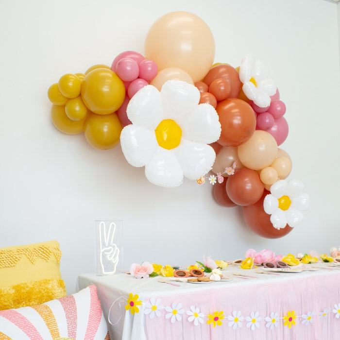 Balloon garland wall display with white daisy balloons and yellow, pink, peach, and orange