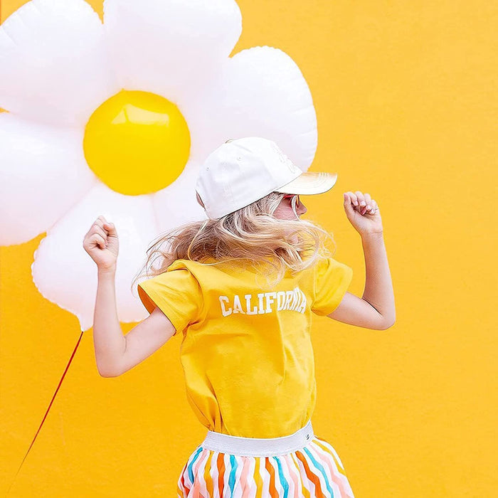 Yellow shirt child holding white daisy balloon with yellow center